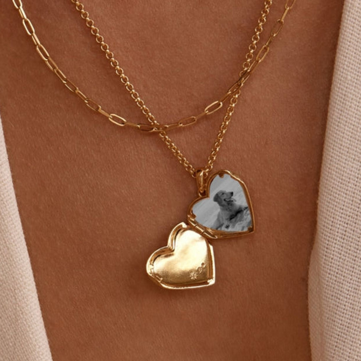 Gold heart-shaped necklace with a photo pendant on a person's neck