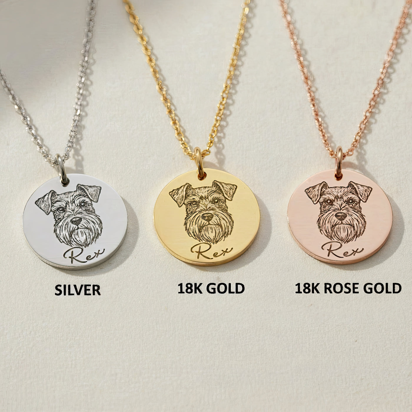 Three engraved pet portrait necklaces displayed side by side in silver, 18K gold, and rose gold finishes, each featuring a dog illustration and name engraving.