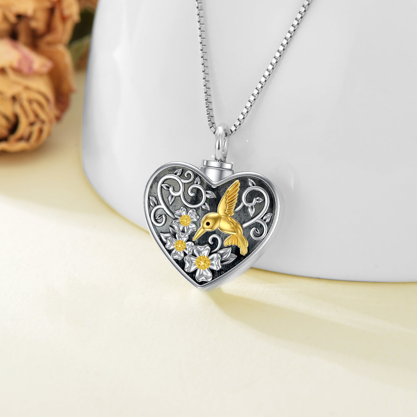 Heart-shaped pendant with gold hummingbird design on a white surface