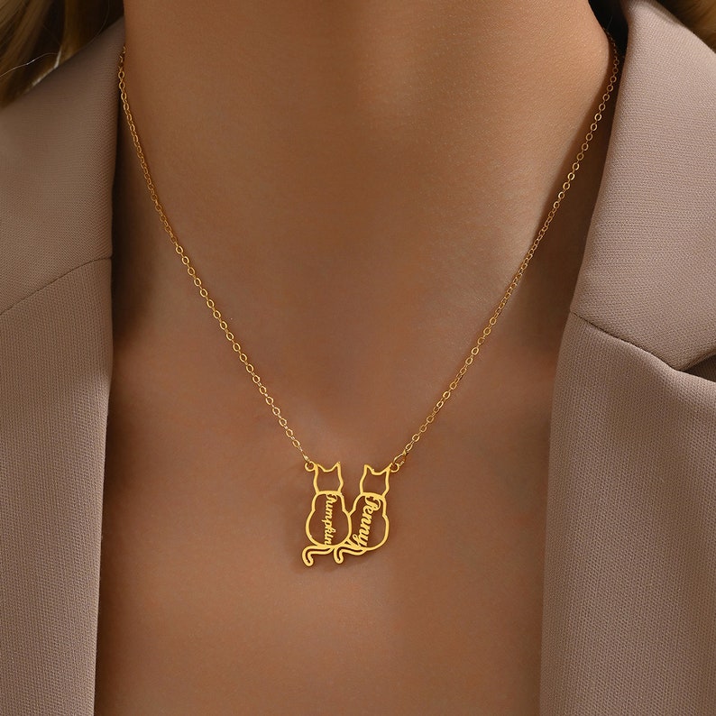 Gold necklace with a cat-shaped pendant on a person wearing a beige blazer.