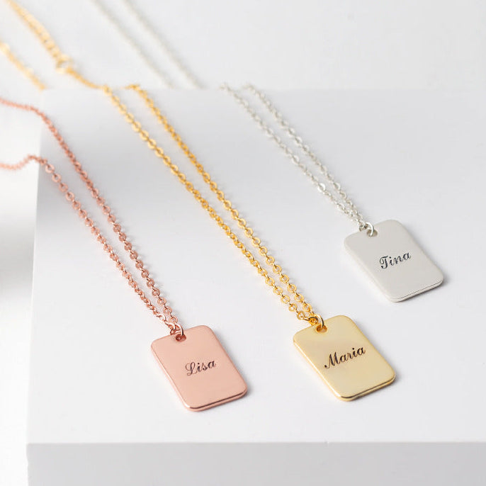 Three necklaces with engraved name tags on a white box