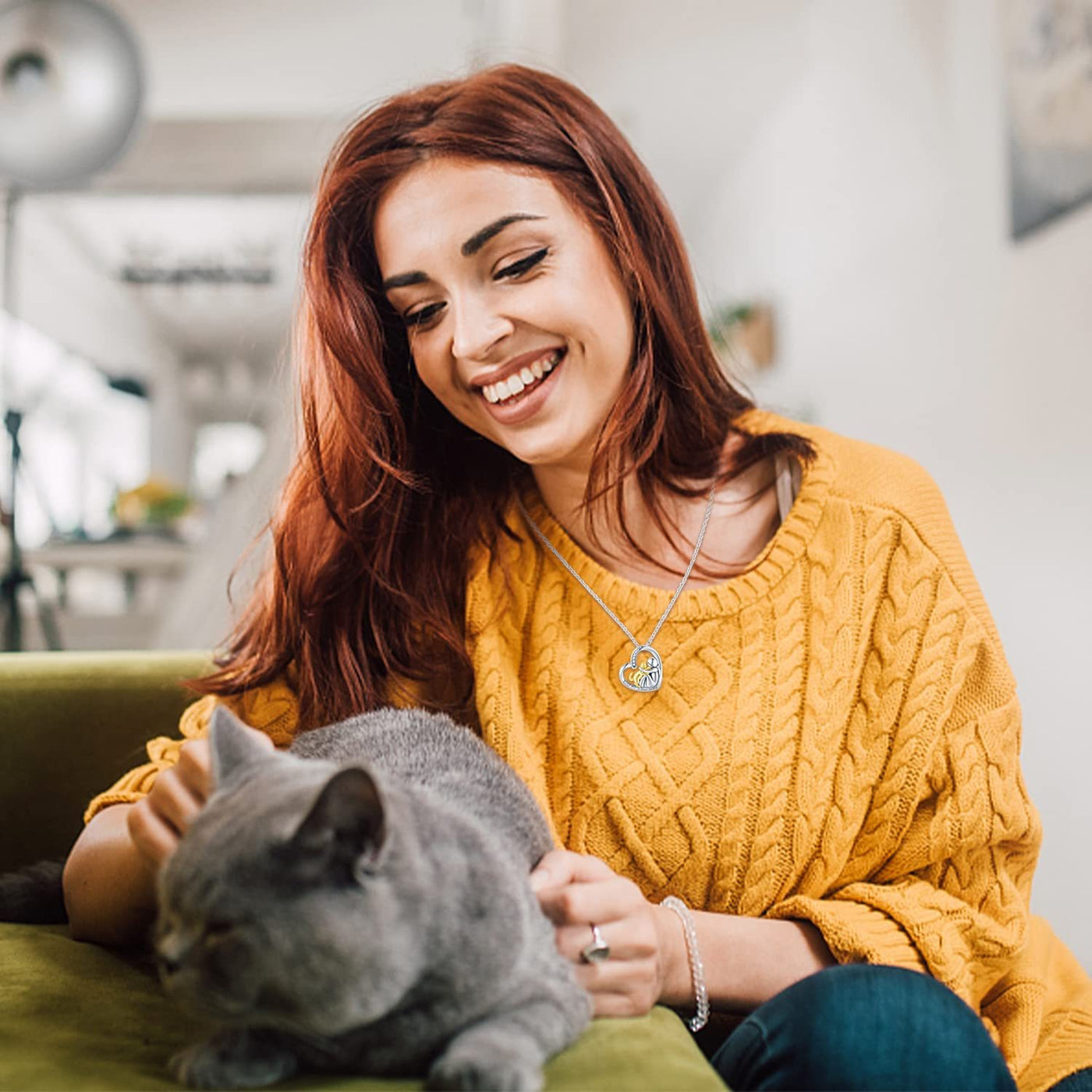 Woman in a yellow sweater petting a gray cat indoors