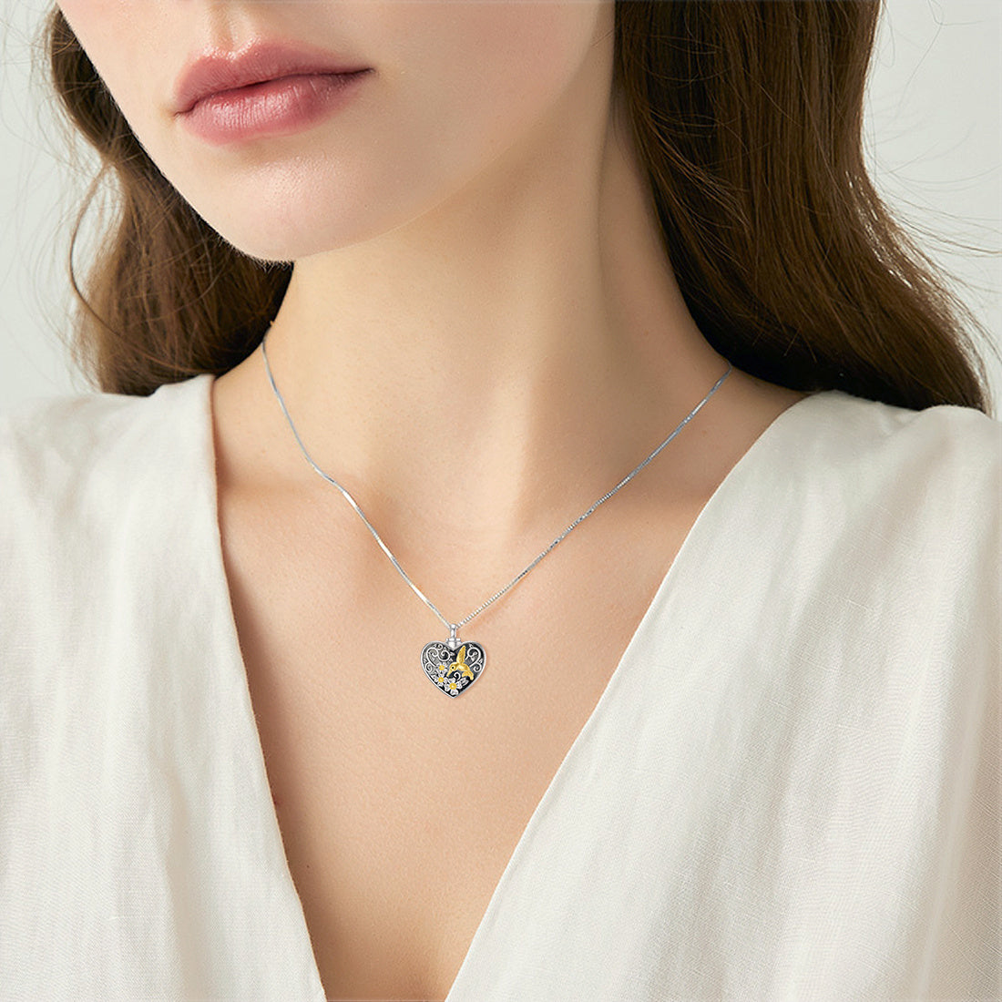 Heart-shaped necklace with blue and yellow accents worn by a model in a white top.