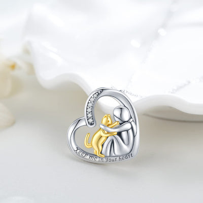 Heart-shaped pendant with a gold cat and silver woman figure, 'Keep me in your heart' text on a white background.