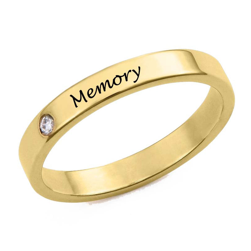 Gold ring with 'Memory' engraving and a small diamond on a white background