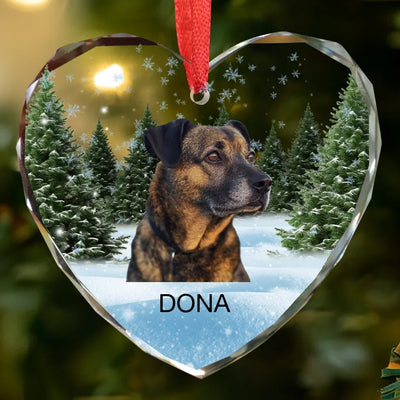 Heart-shaped glass ornament featuring a photo of a dog, surrounded by a winter forest scene, ideal as a pet memorial keepsake