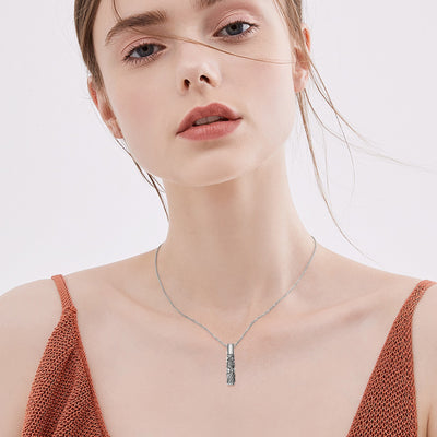 Woman wearing a silver necklace against a plain background