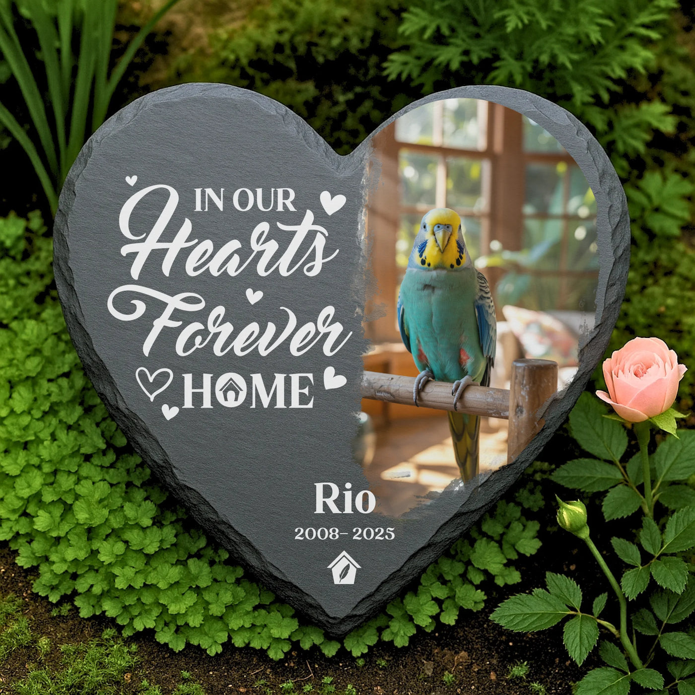Custom engraved heart-shaped slate memorial for parakeet Rio, with engraved quote “I’ll miss you for the rest of mine,” surrounded by flowers and greenery.