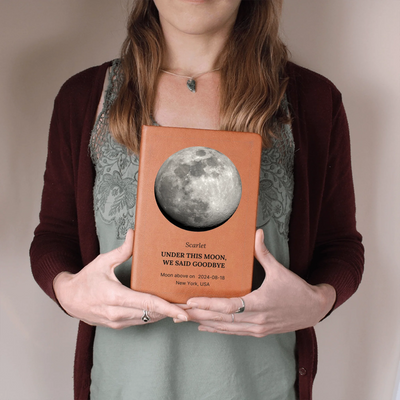 Person holding personalized moon-phase vegan-leather memorial journal with custom name and headline on the cover