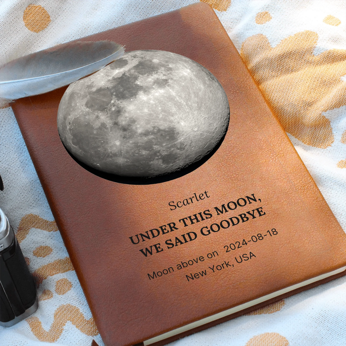 Lifestyle scene: personalized moon-phase memorial journal on soft fabric, accurate lunar phase printed on cover