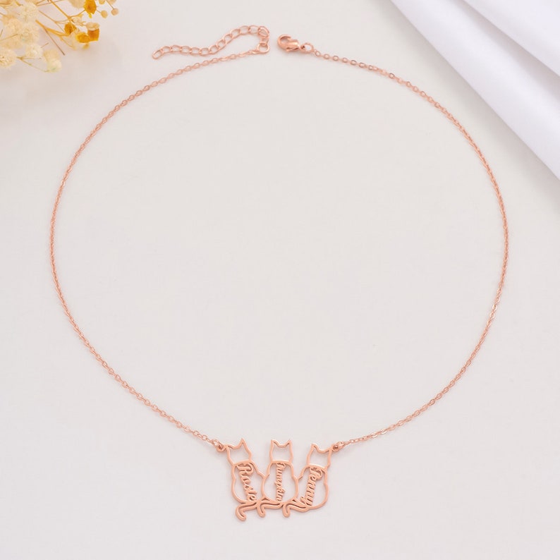 Rose gold necklace with cat-shaped pendants on a light background