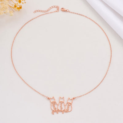 Rose gold necklace with cat-shaped pendants on a light background