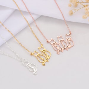 Cat name necklaces with cat designs on a light gray surface