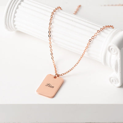 Rose gold necklace with a name tag on a white surface