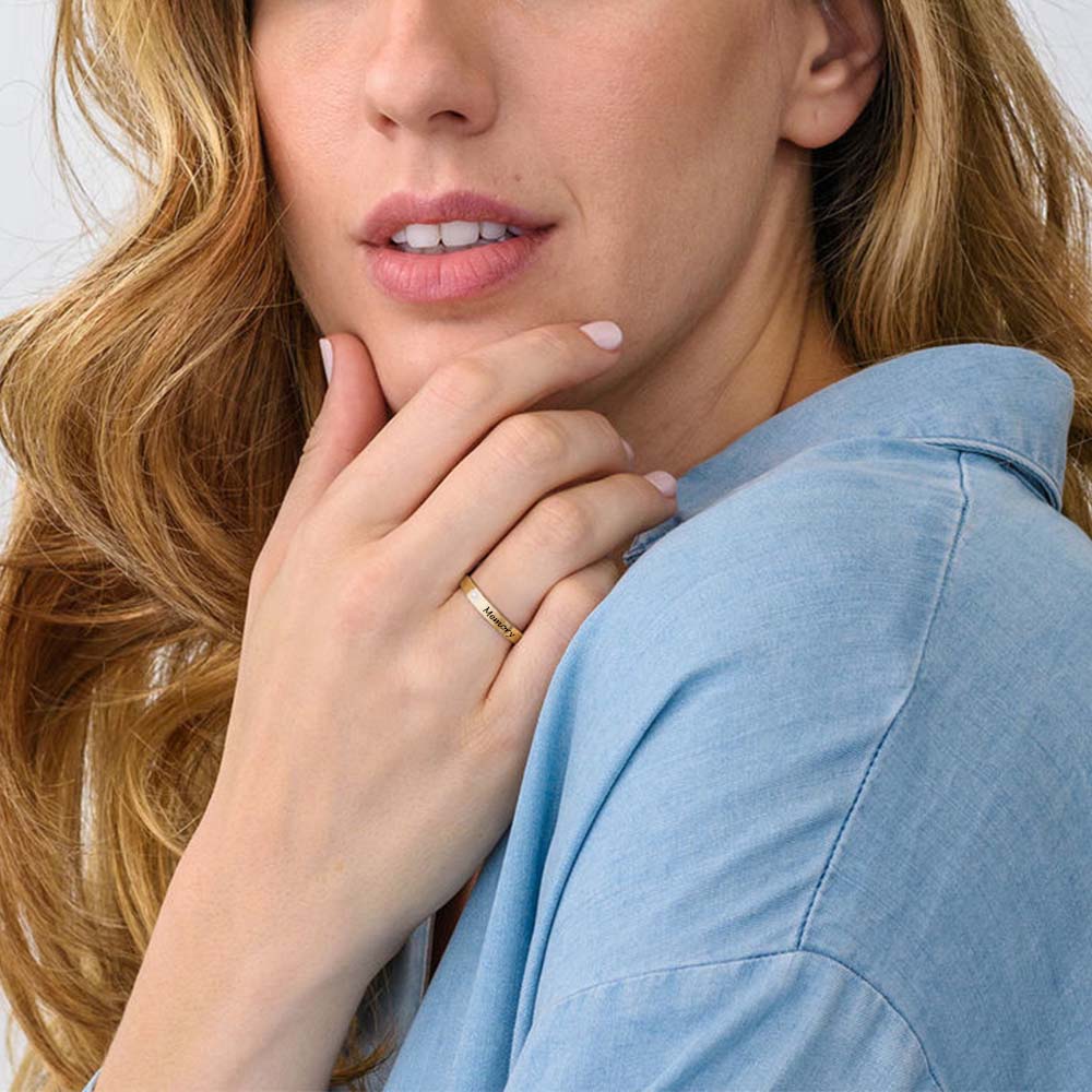 Woman wearing a gold ring on her finger, with a neutral background