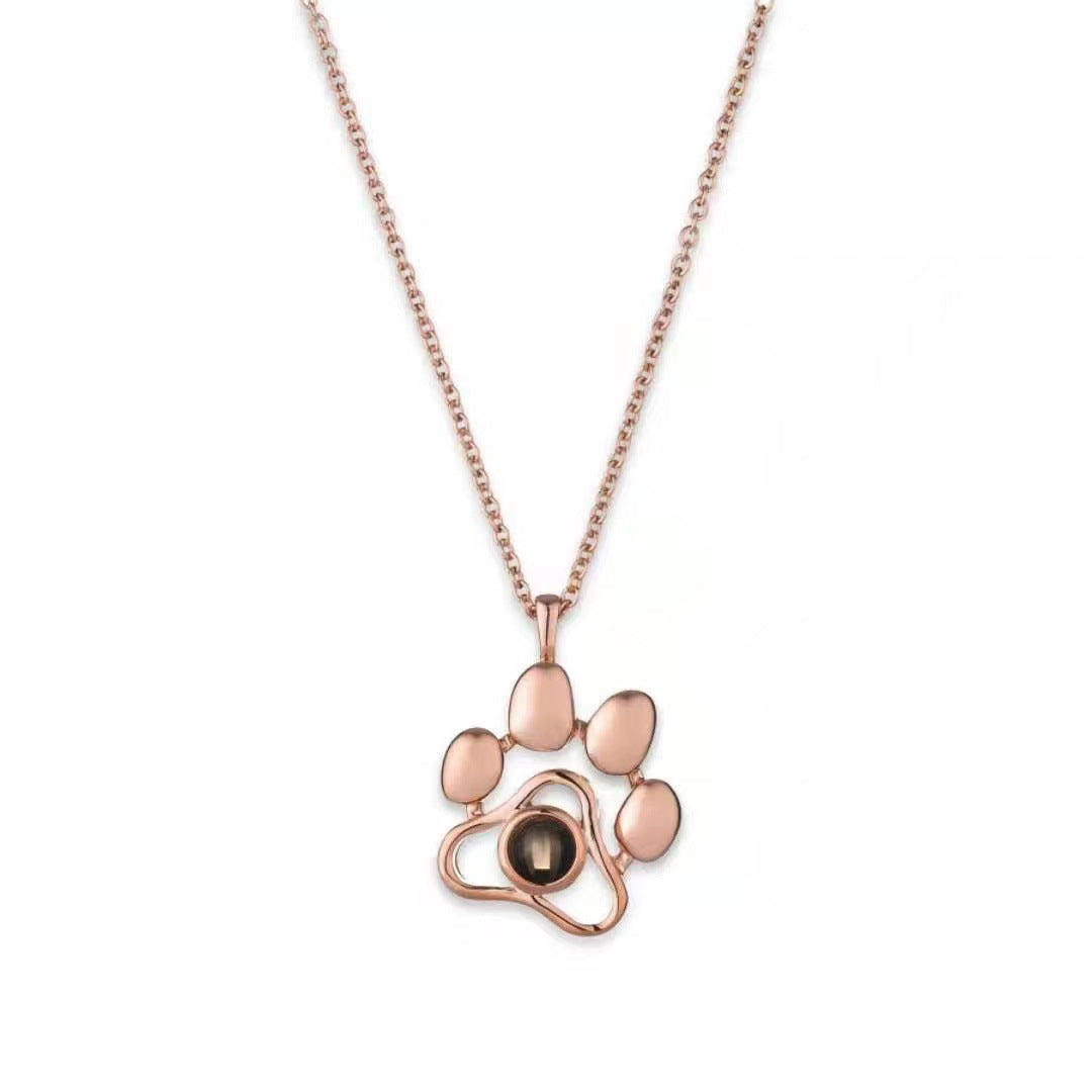 Rose gold paw print necklace on a white background