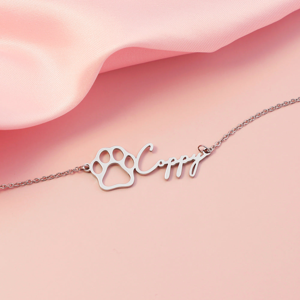 Silver paw print bracelet with a pet  name on a pink fabric background