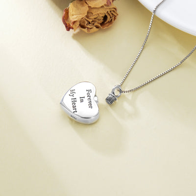 Silver heart-shaped locket with engraved text on a beige background