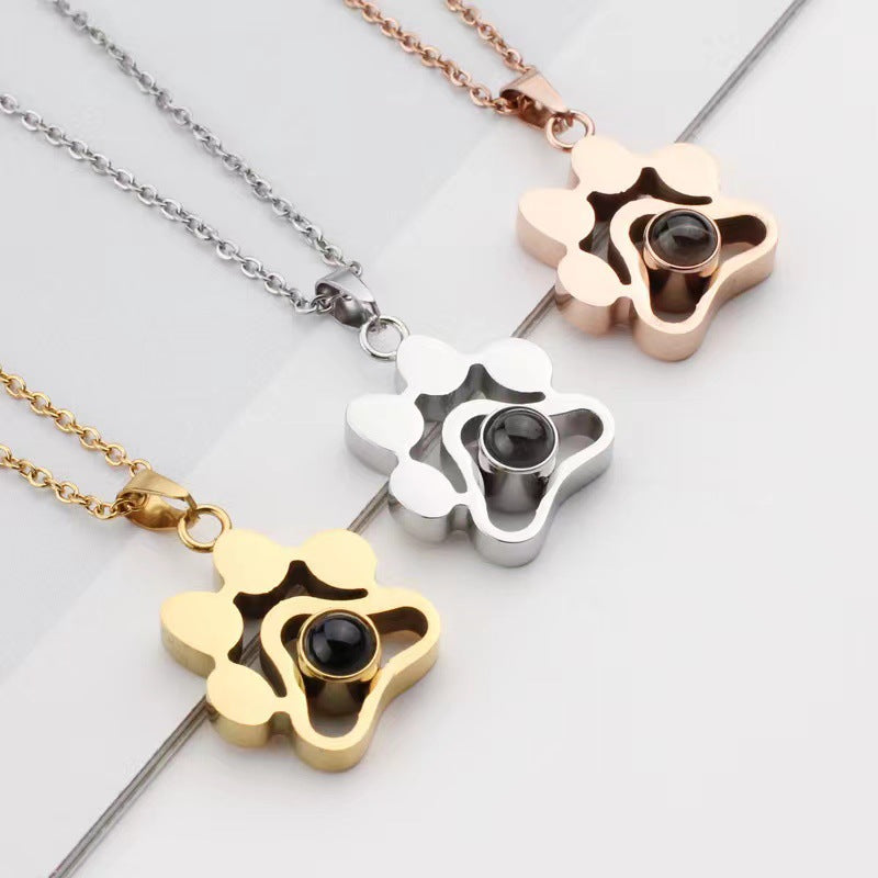 Three paw-shaped pendants in gold, silver, and rose gold on a light gray background.