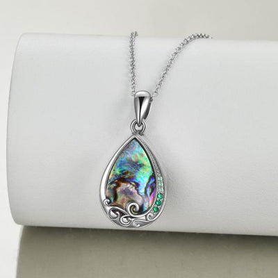 Teardrop-shaped pendant with colorful stone on a white cushion